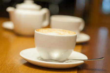 Cup of cappuccino and teapot の写真素材