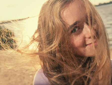 Blonde women on a windy day smiling against seaの写真素材