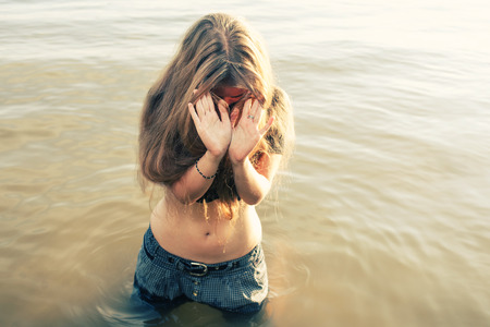 Summertime fun. Young blonde posing in water gesturingの写真素材
