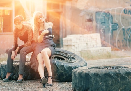 Two women sitting on a truck wheells backlit.の写真素材