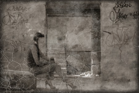 Scratched sepia toned photo women sitting on tire in slum.の写真素材