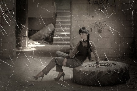 Women sitting on tyre in slum house sepia toned photo with scratchesの写真素材