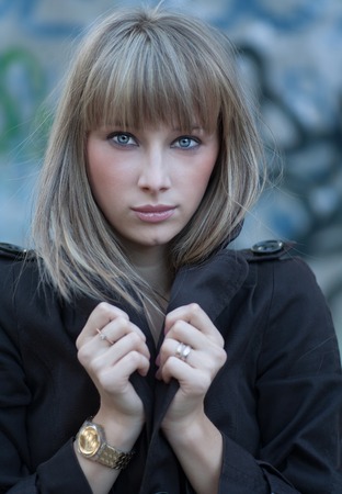 Serious beautiful blond haired women posing against  blue painted aged wall.の写真素材