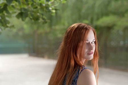 Red haired women looking back outdoor shotの写真素材
