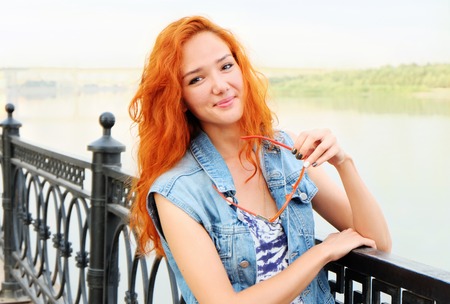 Smiling red haired women standing near river.の写真素材