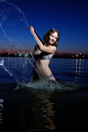 Pretty sexy woman in bikini splash out the water outdoors.の写真素材