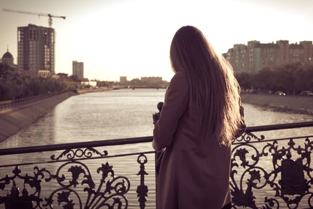 Rear view of long haired women sepia toned, retro portrait of a beautiful girl against water の写真素材