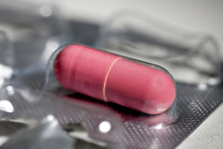 One red pill in blister macro imageの写真素材