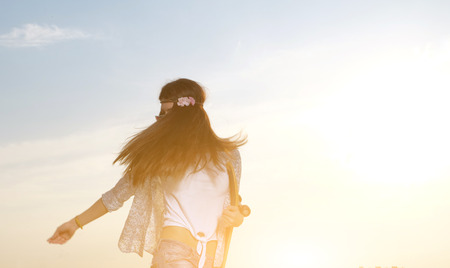 A young woman holding skateboard in her hands. The girl in joyful feelings. Outdoors, lifestyle. Full of sunshine image. A lot of copyspace.の写真素材