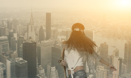 Brunette women with skateboard in her hands on NY City background.の写真素材