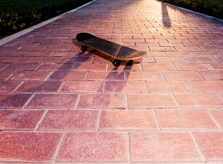 Vintsge skateboard is on paved surface backlit by sunset. Toned image instagram warm colorの写真素材