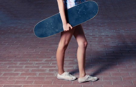 Side view of young women with skateboard warm toned color の写真素材