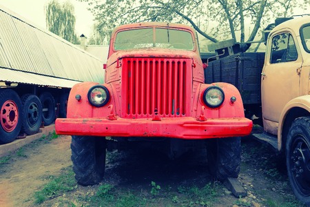 Old rusty red farm trucks fading in time front view.