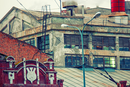 Old power plant buiding with steam from chimney on the roof toned image. Colorized shot old film color imitation.の写真素材