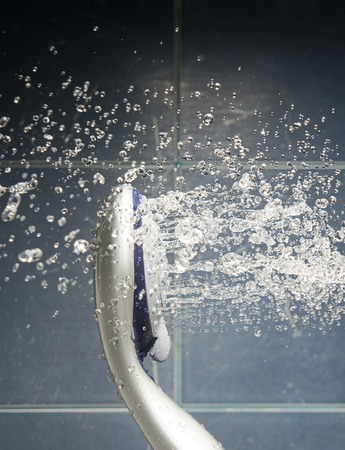 Shower head with  water drops spread obout. Water drops levitate about in bathroom.の写真素材