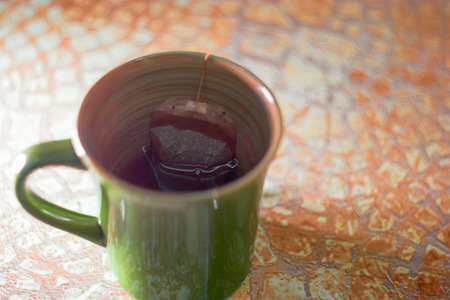 Green cup of tea with teabag on table with copy space, selective focus, shallow DOF.の写真素材