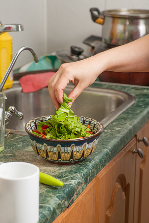Young woman hand preparing vegetable salad in the kitchenの写真素材