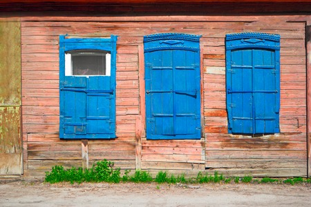 Old wooden window of slum house painted in red and blue color  in Astrakhan, Russia