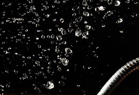 drops of water levitate on a dark background and water pipe.の写真素材