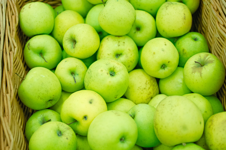 Fresh green apples in wicker tray of a supermarketの写真素材