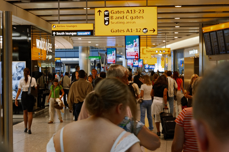 London, UK, 03 Jul. 2009: Many passengers walking toward A13-23 Gates in Heathrow Airport. Different direction and AD banners about.のeditorial素材