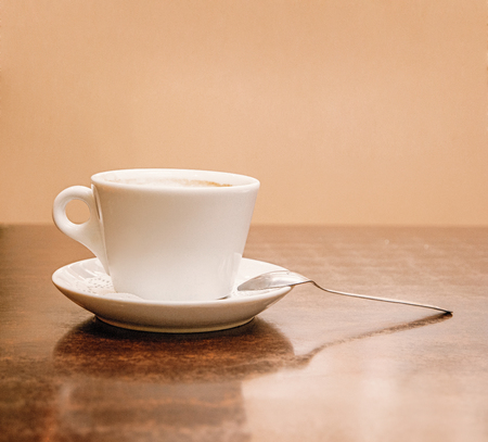 Coffee cup side view on wooden table. A lot of space for text on wall on background.の写真素材
