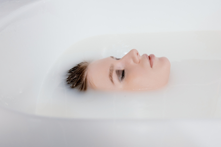 Face of Attractive woman in milk bath side view, with copyspaceの写真素材