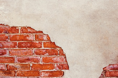 Half plastered brick wall. Half weathered brick wall a lot of copy space.Cracked wall. Aged architecture detail. Grunge brick wall half plastered.の写真素材