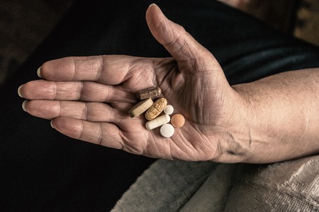 Above view of pills and tablets on senior woman palm vintage tonedの写真素材