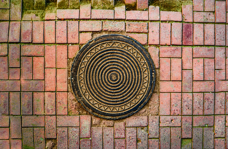 Rusty manhole in pavement from aboveの写真素材