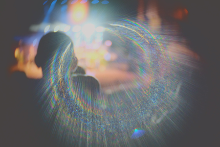 Rear Back View Blurred People looking at stage with rainbow flare.の写真素材