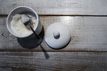 Sugar with a scoop in a bowl. On a weathered white wooden background.の写真素材