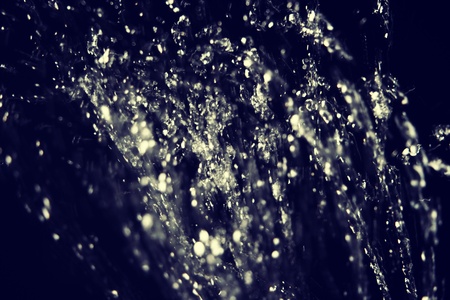 Water drops fly or frozen in the air on dark background. Levitation of water drops on dark.