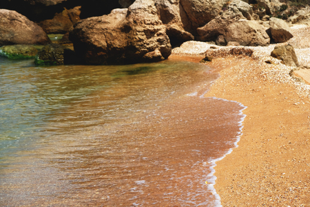beautiful waves break on the sand and rocks a lot of copyspaceの写真素材