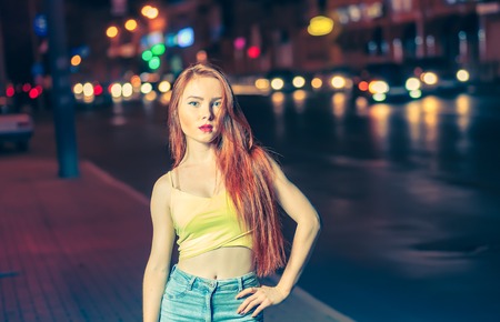 Gorgeous ginger haired girl, portrait in night city setting. Street fashion style portrait of young...