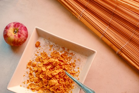 Organic Fitness Eating. Bowl of crispy cornflakes and red appl near top view