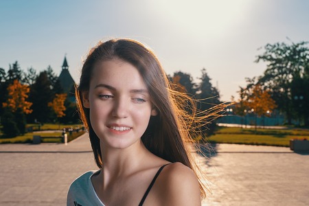 Happy Cute Girl looking down in summer day backlitの写真素材