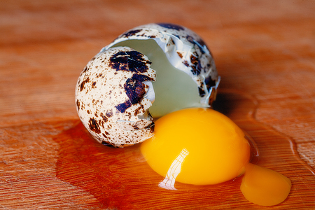 Shell And Yolk. Broken Quail Egg On Wooden Cooking Board Angle Viewの写真素材