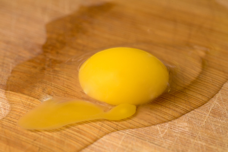 Brocken egg macro photograph on wood plankの写真素材