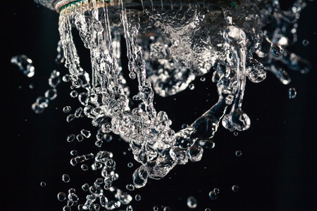 Water drops levitating about shower head on black background