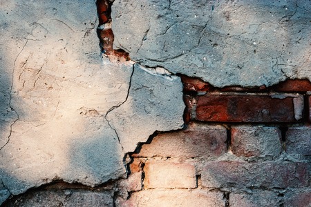 Brick wall with damaged plaster.