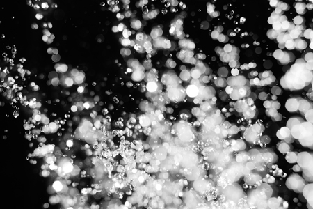 Water drops levitate in the air and spot of defocused light on background, stream of water fly in the airの写真素材