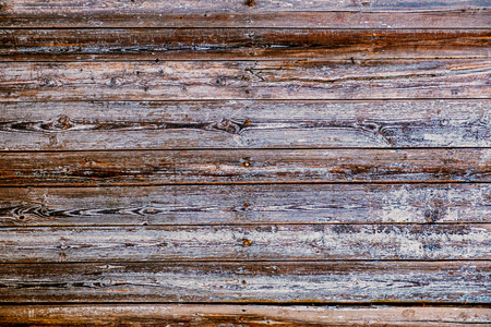A fence of dark obsolete boards. Blank background with a texture of wooden slats with heads of nailsの写真素材