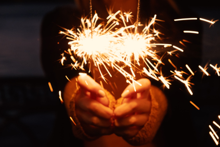 Close-up of blurry bruning sparklers in the night time, lets celebrate Christmasの写真素材