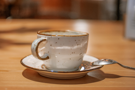 Side view of Empty ceramic cup on wooden table with silwer spoon near on sourcerの写真素材