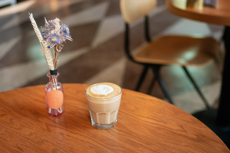 Dry flowers on tabletop in cafe with small glass of flat-white coffee standing on side viewの写真素材