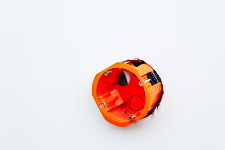 Orange install box for electric outlet in hole of plastered wall, copyspace, selective focus....