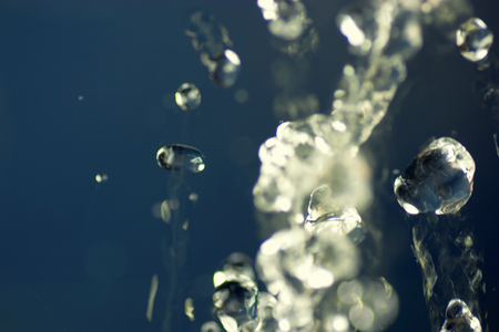 Abstract macro photo of water drops fly in the air levitation water on dark blue background.の写真素材