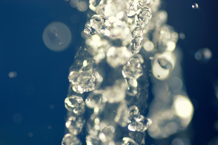 Freshness concept for SPA health treatment. Flying drops of water frozen on a blue background. Splashed water drops in an airの写真素材