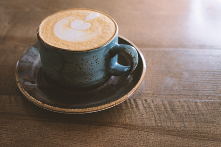 Vintage looking Coffee cup with perfect latte art on foam side view on tabletop with copy spaceの写真素材